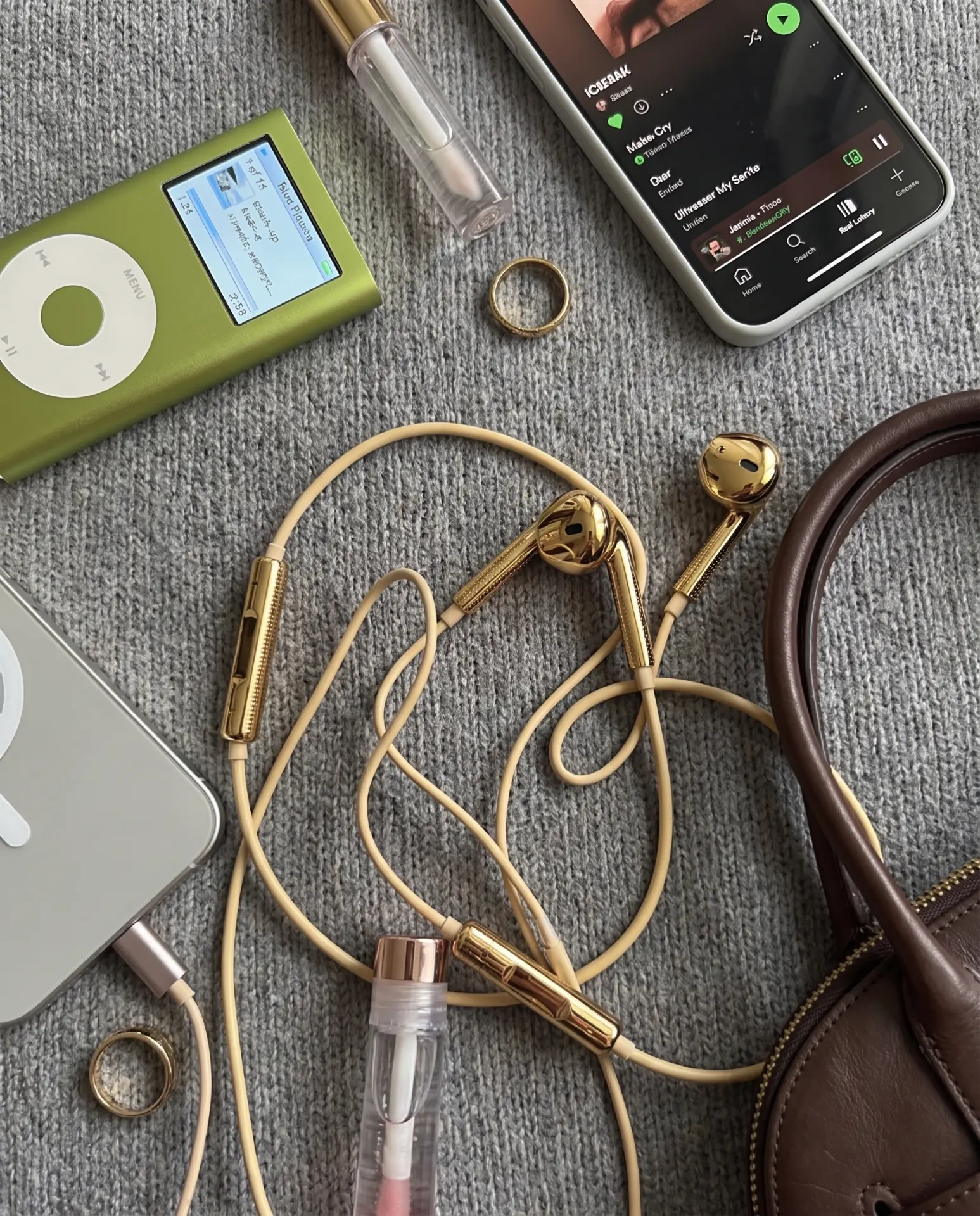 Gold Auralie earbuds flatlay with an iPod, phone and gold rings