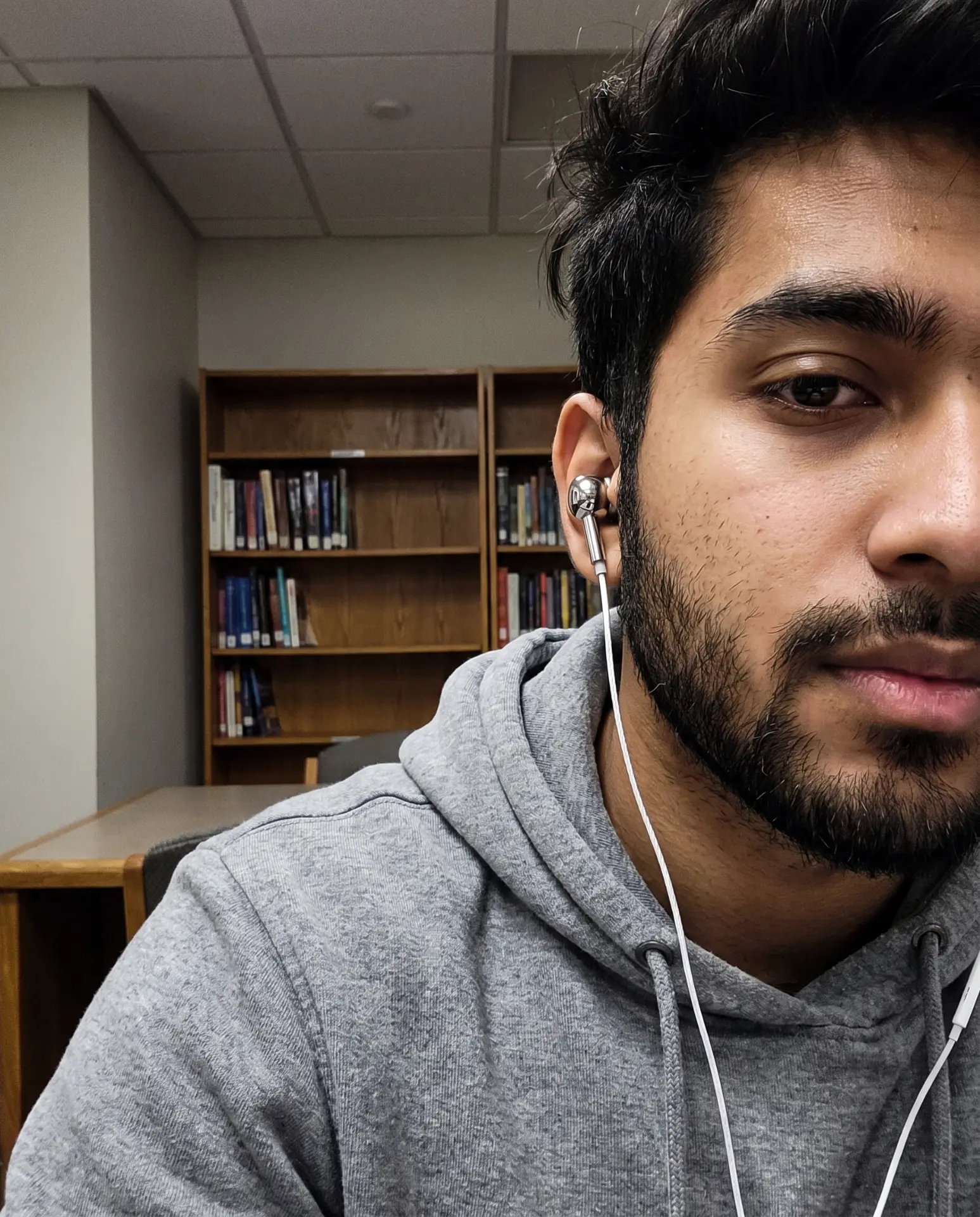 Selfie wearing a chrome Auralie earbud in a library