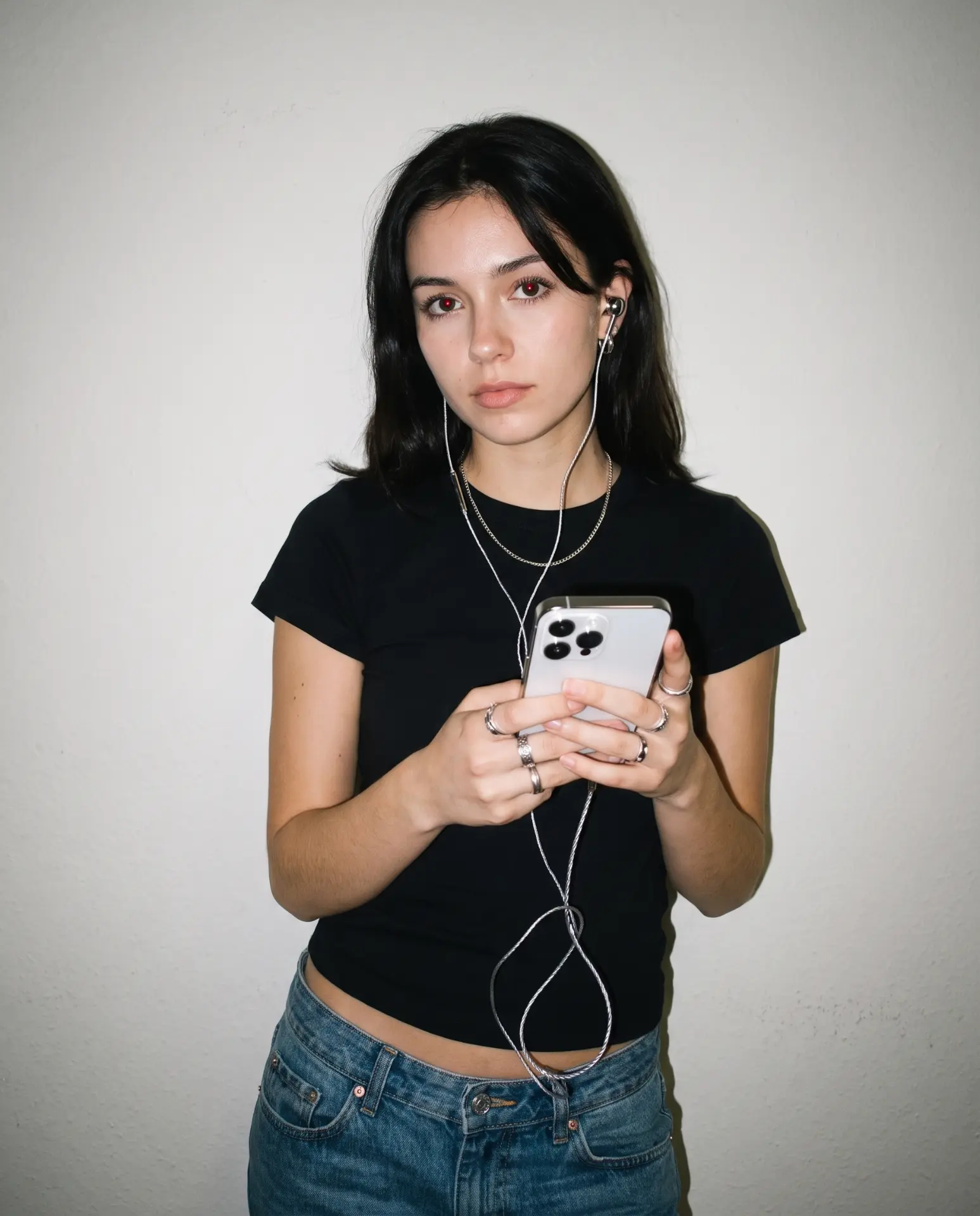 Wearing silver Auralie earbuds with a black tee and stacked rings